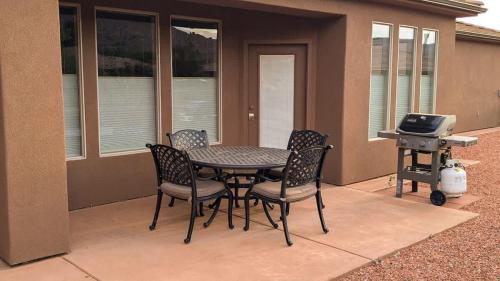 a patio with a table and chairs and a grill at Coral Cliff View - Amazing Views and Pool in Kanab