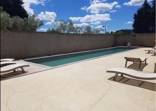 a swimming pool with two chairs and a fence at CHEZ BABOU studio d'artistes avec piscine, parking in Nîmes