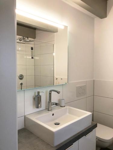 ein weißes Badezimmer mit Waschbecken und Spiegel in der Unterkunft Schlei 48 in Borgwedel