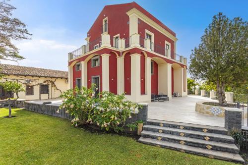 a large red and white building with a yard at Badimà - Villa con piscina in Aci SantʼAntonio