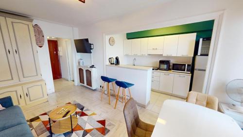 - une cuisine avec des placards blancs et des tabourets bleus dans une pièce dans l'établissement Charmant studio en bord de mer, à Roquebrune-Cap-Martin