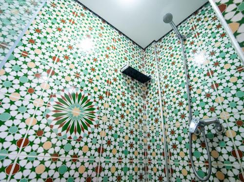 y baño con ducha y pared de azulejos. en Appartement résidence, en Taghazout