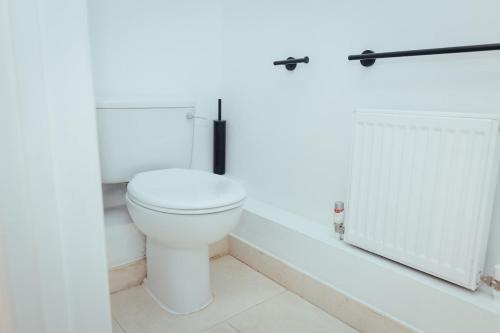 a white bathroom with a toilet and a door at 5 Bed Family Home- Free Parking in Woodham Ferrers Station
