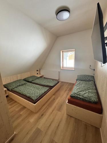 two beds in a small room with a window at Penzion a Restaurace Pod Sjezdovkou in Čenkovice