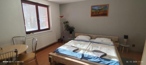a bedroom with a bed and a table and a window at Guest House Zuzana in Habovka