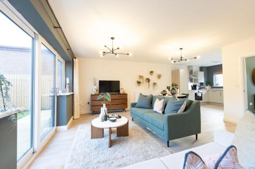 a living room with a blue couch and a table at The Show Home - Grange Meadows 7 Adults 2 Kids in Mossley