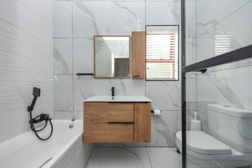 a bathroom with a sink and a toilet and a mirror at Modern 2 Bedroom apartment with club house pool in Sandton