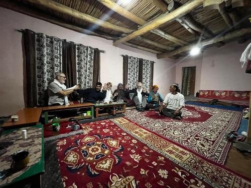 a group of people sitting in a room with a red rug at Khangsar homestay in Padam