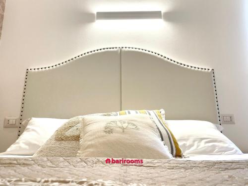 a bed with a white headboard with a light above it at BARI ROOMS Abate Gimma in Bari