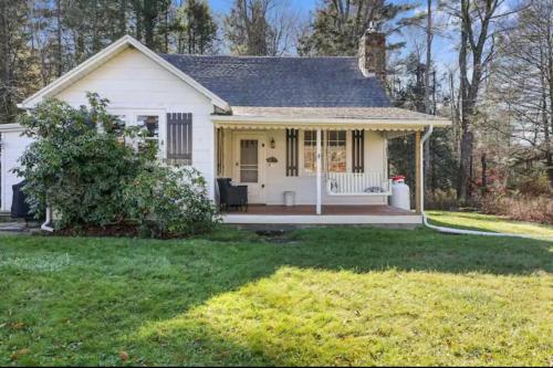 a small white house with a porch and a yard at The Babbling Brooke in Blakeslee