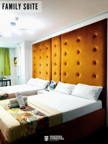 a bedroom with two beds and a large headboard at Haeinsa Condotel in Manila