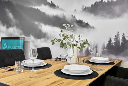 a wooden table with plates and wine glasses on it at Lagom by Mountain ways in Abertamy