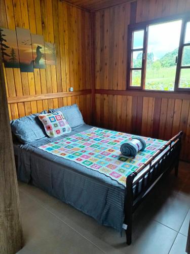 a bedroom with a bed in a wooden wall at Cabana Harmonia in Barracão