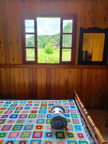 a bedroom with a quilt on a bed with a camera on it at Cabana Harmonia in Barracão
