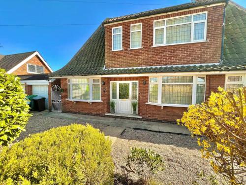 a brick house with white windows and a driveway at Bramcote Lane Luxury Apartments in Nottingham