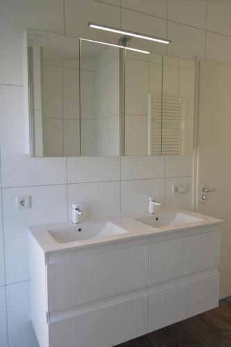 a bathroom with two sinks and a large mirror at Schaelsbergerbosch- 2 Bath FireplGarde in Valkenburg