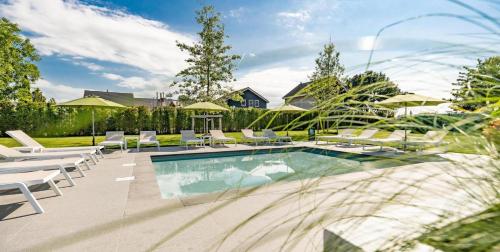 Schaelsbergerbosch- 2 Bath FireplGarde في فالكنبورخ: حمام سباحة مع كراسي وطاولات بيضاء ومنزل