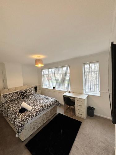 a bedroom with a bed and a desk and windows at Bramcote Lane Luxury Apartments in Nottingham