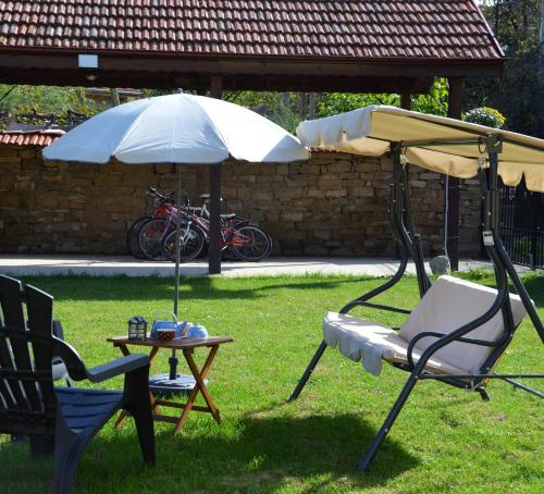 una sedia e un ombrello e un tavolo in un cortile di The Village Cottage a Natsovtsi