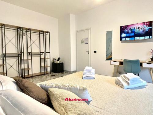 a room with two beds and a tv on the wall at Barirooms Piccinni in Bari