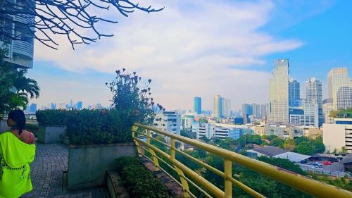 a person sitting on a ledge looking at a city at River View Active 02 in Bangkok