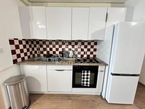 une cuisine avec des armoires blanches, un évier et un réfrigérateur dans l'établissement Appartement idéal famille - Centre-ville Juan-les-Pins, à Antibes