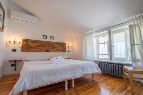 a bedroom with a white bed and two windows at Mansarda 64 in Castelnuovo del Garda