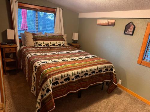 a bedroom with a bed with a comforter and a window at Gonzales Cozy Little Bear Cabin in Ruidoso