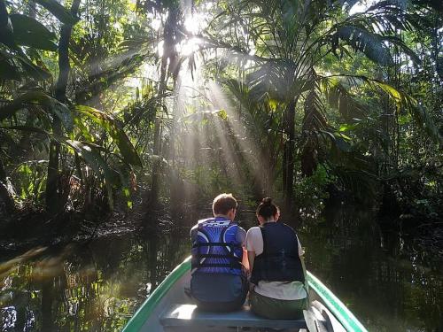 two people sitting on a boat in the water at Casa Los Delfines in Tortuguero