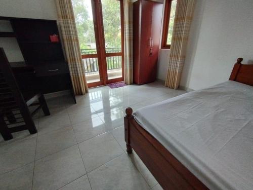 a bedroom with a bed and a balcony at Villa Muthuwin in Panadura