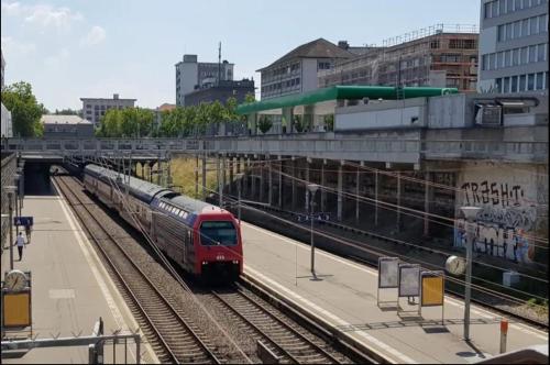 a red train is pulling into a train station at KAYA Zurich Apartment 3B - Downtown 2BR Deluxe Apt in Zürich