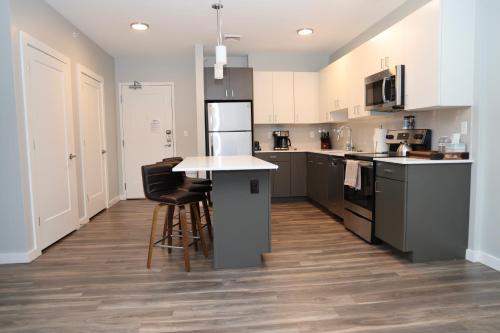 a kitchen with black and white appliances and wooden floors at Luxury apartment with gym, steps from commuter rail #4011 in Reading