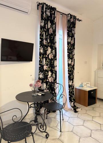 a room with a table and two chairs and a television at Pharus Miseni Suites and rooms in Bacoli