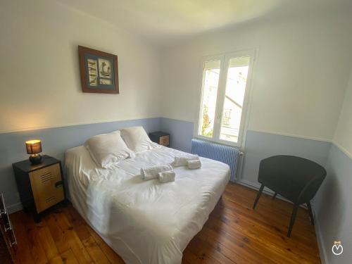 une chambre avec un lit avec une chaise et une fenêtre dans l'établissement Maison Deauvillaise, à Deauville
