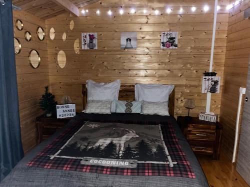 a bedroom with a bed in a wooden wall at Les Chalets de marie 2 - Vue mer, Jacuzzi SPA privatif dans le chalets Sans vis à vis in Saint-Denis
