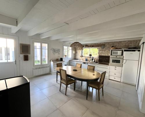 une grande cuisine avec une table et des chaises en bois dans l'établissement Maison LA BEURELIÈRE proche Plage, à Sainte-Marie de Ré