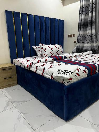 a bed with a blue headboard in a room at Esthercy Hotels in Okunola