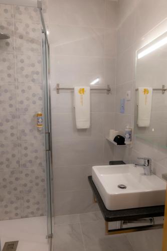 a white bathroom with a sink and a shower at Figuras Mágicas in Trancoso