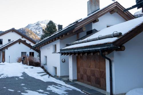 a house with a garage with snow on the roof at Chalet a Saint Moritz with Sauna Privata in Pontresina