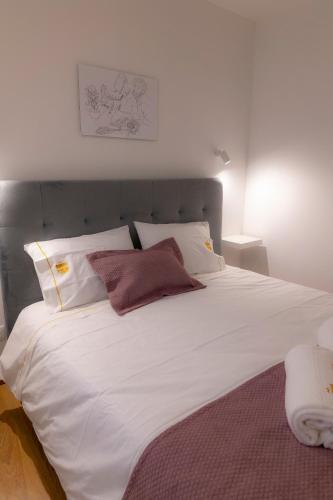 a large bed with white sheets and pillows at Figuras Mágicas in Trancoso