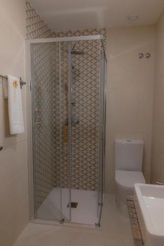 a bathroom with a shower with a toilet and a sink at Figuras Mágicas in Trancoso