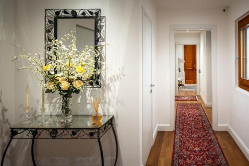 a hallway with a table with a vase of flowers at Marcus Suite in Cagliari