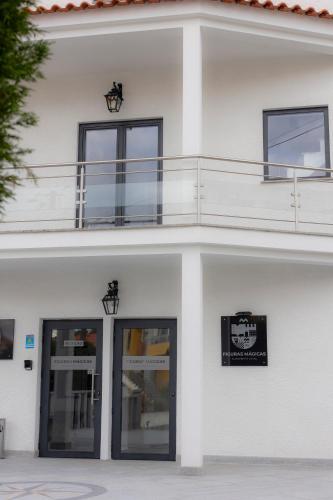 a white building with a balcony on top of it at Figuras Mágicas in Trancoso