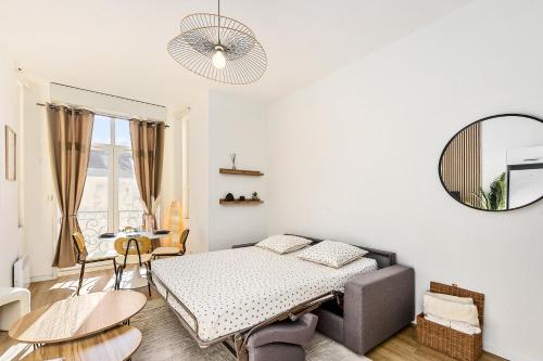 une chambre avec un lit, une table et un miroir dans l'établissement JARDIN DES MUSES II - Somptueux 2 pièces - Carré d'or Menton, à Menton