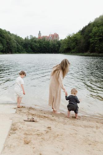 a woman and two children playing in the sand on the beach at Dobre Historie in Leśna