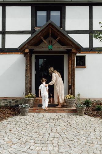 a woman and a child standing on the porch of a house at Dobre Historie in Leśna