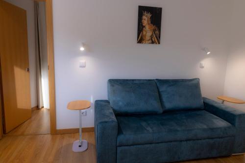 a living room with a blue couch and a table at Figuras Mágicas in Trancoso