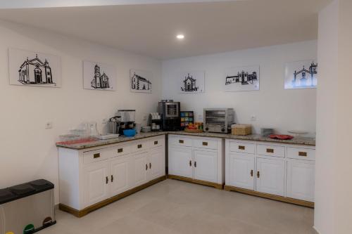 a kitchen with white cabinets and appliances on the wall at Figuras Mágicas in Trancoso