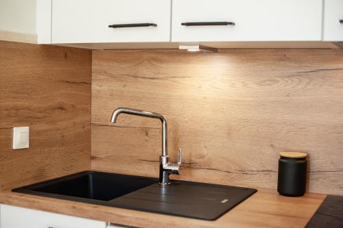 - un évier de cuisine avec un plan de travail noir dans l'établissement JARDIN DES MUSES II - Somptueux 2 pièces - Carré d'or Menton, à Menton