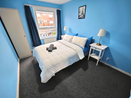 a blue bedroom with a bed and a window at 2 Bedroom Flat Next to Lord's Cricket Ground, Central London in London